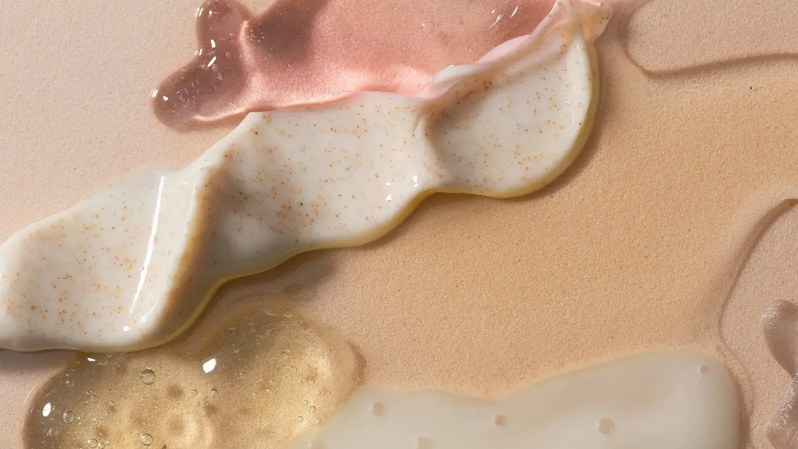 Swatches of gel, cream and serum textures on a beige surface